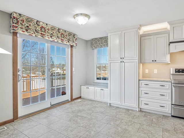 interior space with white cabinets, stainless steel range with electric cooktop, visible vents, and baseboards