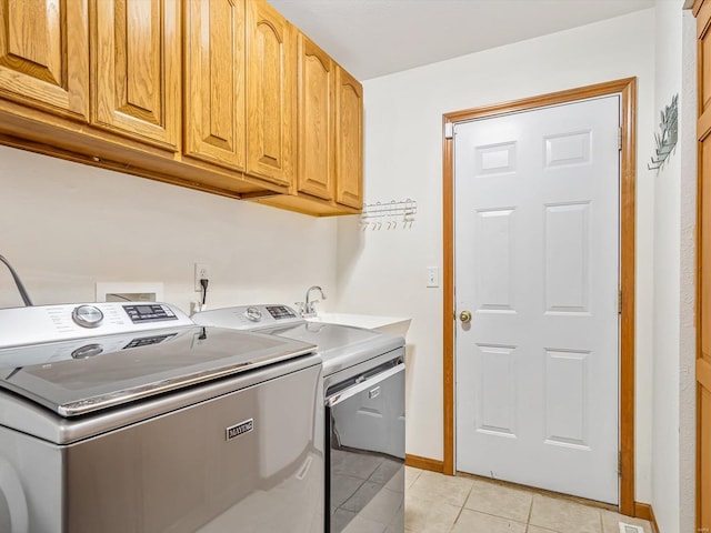 washroom with baseboards, light tile patterned flooring, cabinet space, and washer and dryer