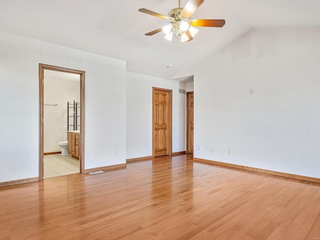 unfurnished room featuring vaulted ceiling, light wood-type flooring, and baseboards