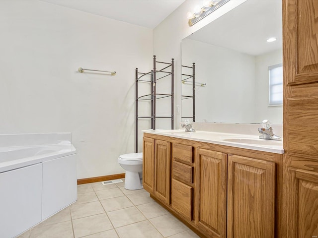 bathroom with double vanity, a sink, toilet, and tile patterned floors