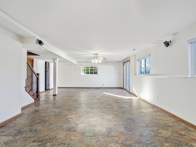 spare room with visible vents, a ceiling fan, stairs, baseboards, and stone finish floor