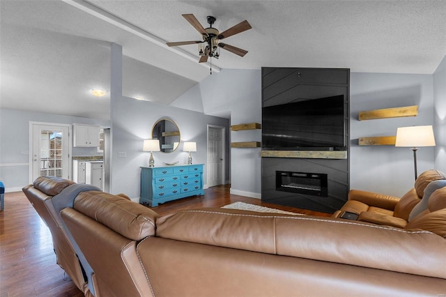 living room with baseboards, vaulted ceiling, a fireplace, wood finished floors, and a textured ceiling