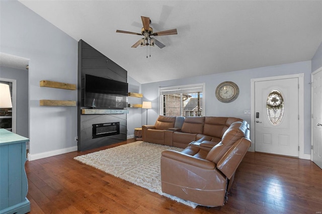 living area featuring a ceiling fan, baseboards, vaulted ceiling, hardwood / wood-style flooring, and a large fireplace