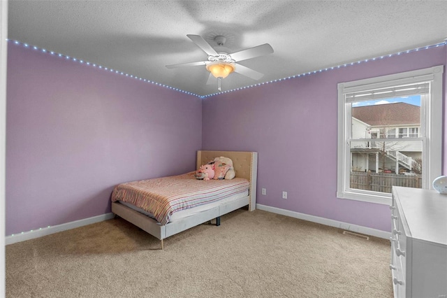 bedroom featuring baseboards, light carpet, and a textured ceiling