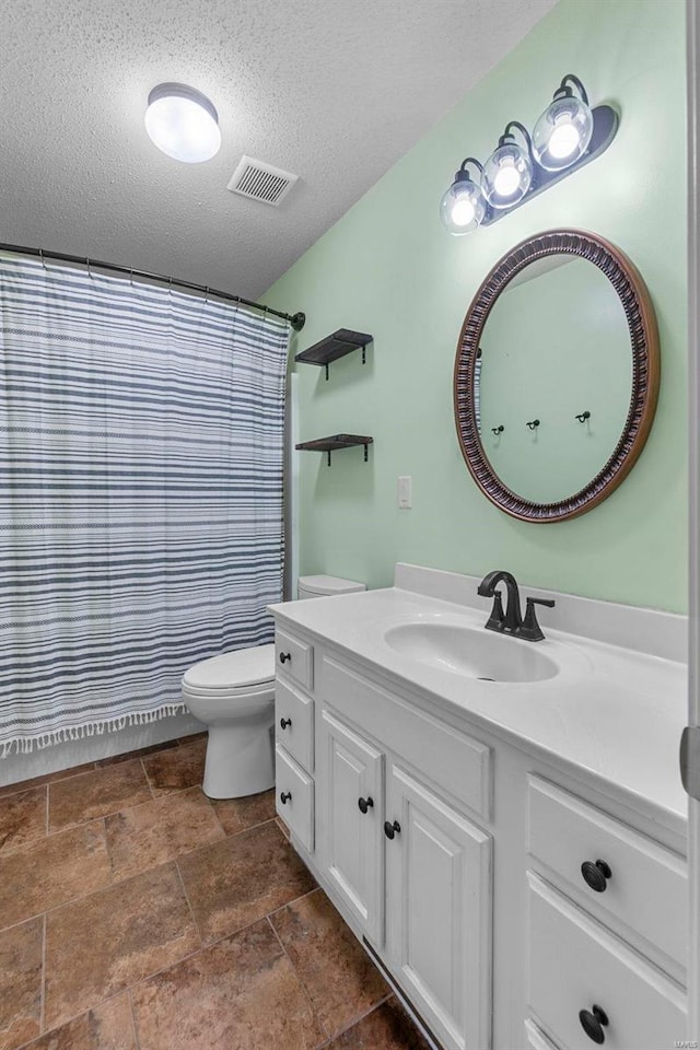 full bath with visible vents, toilet, stone finish floor, a textured ceiling, and vanity