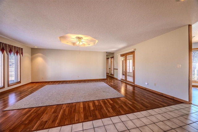 unfurnished room with baseboards, a textured ceiling, a ceiling fan, and wood finished floors