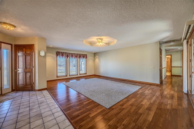 entrance foyer with a textured ceiling, wood finished floors, a ceiling fan, and baseboards