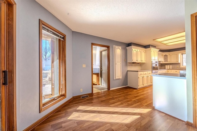 kitchen with light wood-style floors, visible vents, baseboards, and a textured ceiling