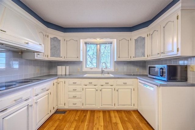 kitchen featuring black electric cooktop, a sink, range hood, dishwasher, and stainless steel microwave