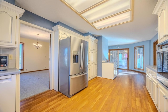 kitchen featuring stainless steel appliances, light countertops, a chandelier, light wood-type flooring, and baseboards