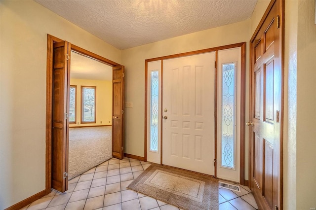 entrance foyer featuring light tile patterned floors, baseboards, visible vents, and a textured ceiling