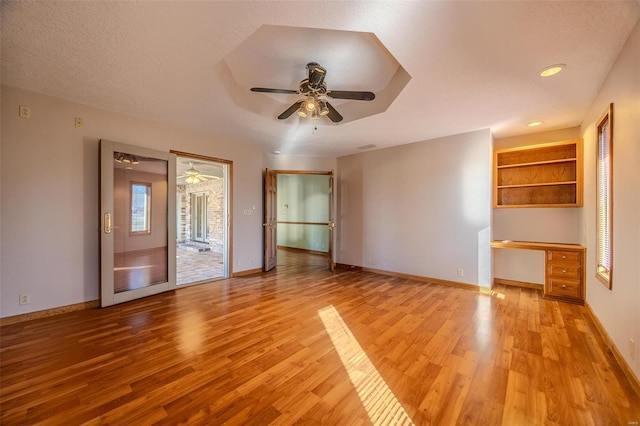 unfurnished living room featuring a healthy amount of sunlight, light wood finished floors, baseboards, and built in study area