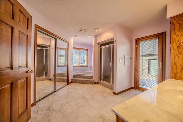 bathroom with vanity, visible vents, baseboards, a bath, and a stall shower