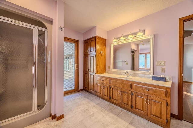 full bath featuring a stall shower, vanity, and baseboards