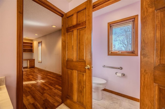 bathroom with recessed lighting, wood finished floors, toilet, and baseboards