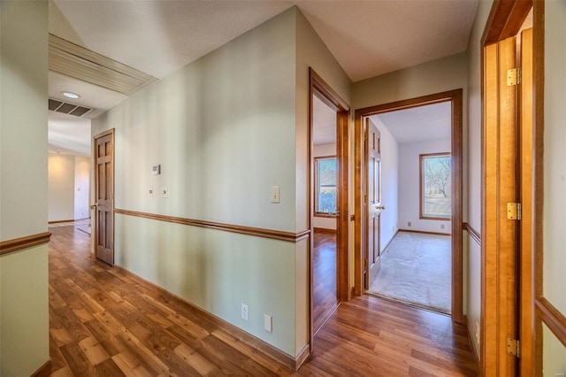 corridor featuring baseboards, visible vents, and wood finished floors