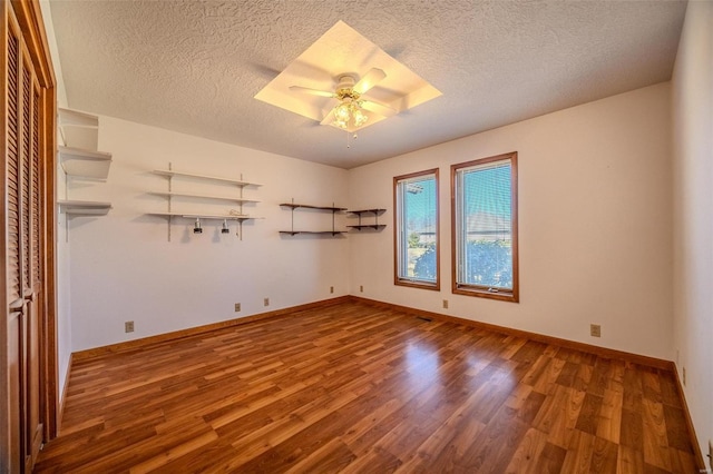 spare room featuring ceiling fan, a textured ceiling, wood finished floors, and baseboards