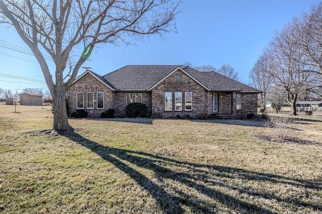 ranch-style house featuring a front yard, brick siding, and roof with shingles