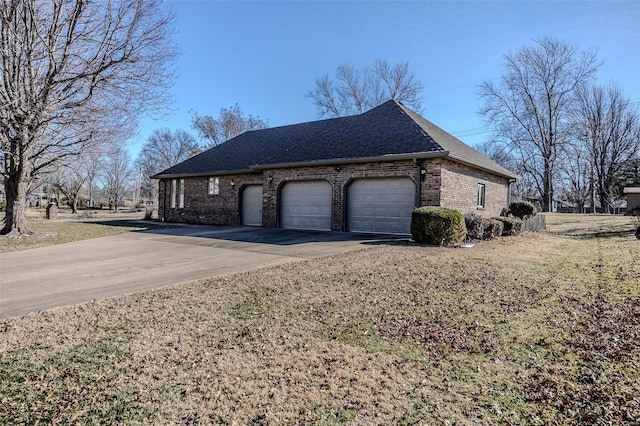 view of side of home with an attached garage, brick siding, a yard, driveway, and roof with shingles