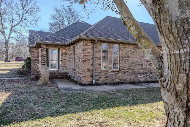 view of property exterior with crawl space, brick siding, a yard, and roof with shingles