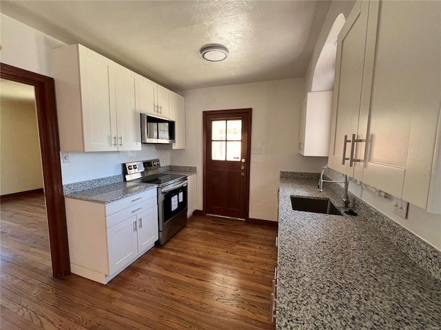 kitchen featuring stainless steel appliances, stone countertops, a sink, and white cabinets