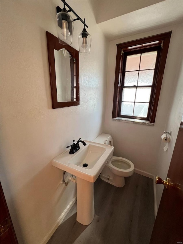 half bath featuring baseboards, toilet, and wood finished floors