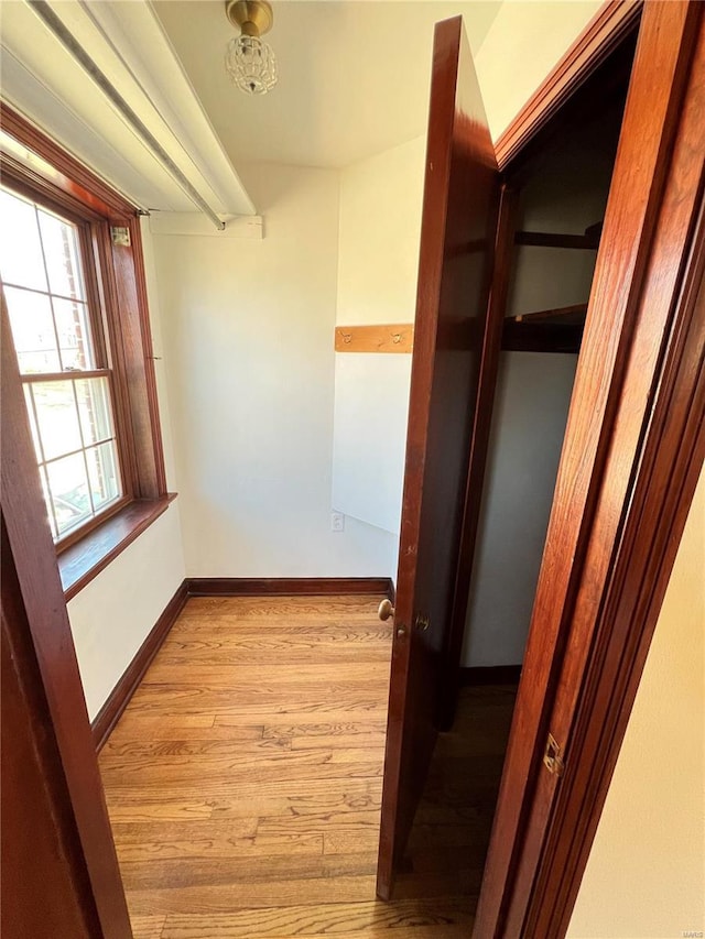 corridor featuring light wood-style floors and baseboards