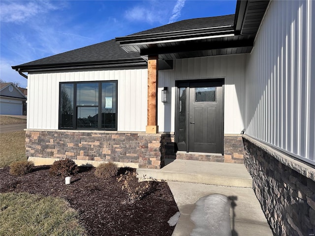 entrance to property featuring stone siding and roof with shingles