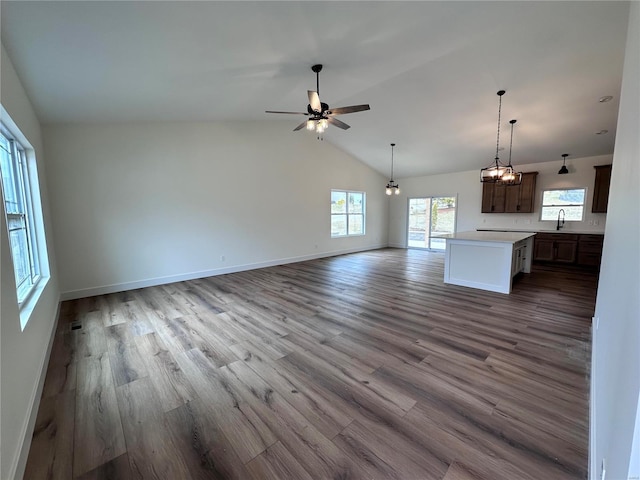 unfurnished living room featuring baseboards, a ceiling fan, light wood-style flooring, vaulted ceiling, and a sink