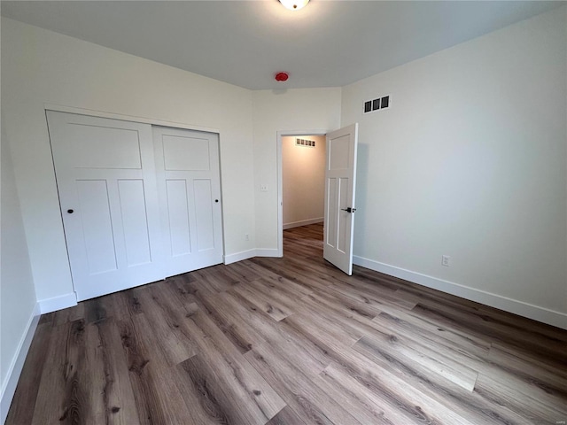 unfurnished bedroom with a closet, visible vents, light wood-style flooring, and baseboards