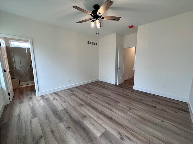 unfurnished bedroom featuring ensuite bath, baseboards, visible vents, and wood finished floors