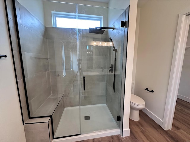 full bathroom featuring toilet, a shower stall, baseboards, and wood finished floors