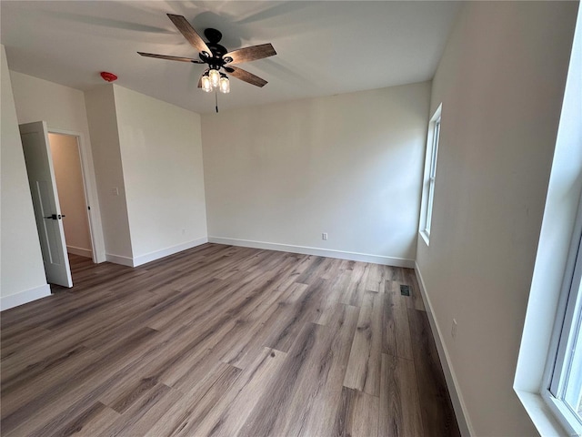 unfurnished room featuring ceiling fan, wood finished floors, visible vents, and baseboards