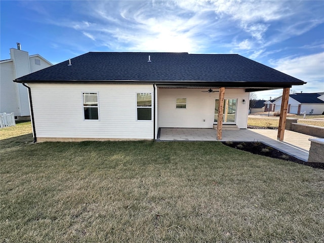 rear view of house featuring a patio, a yard, and a shingled roof