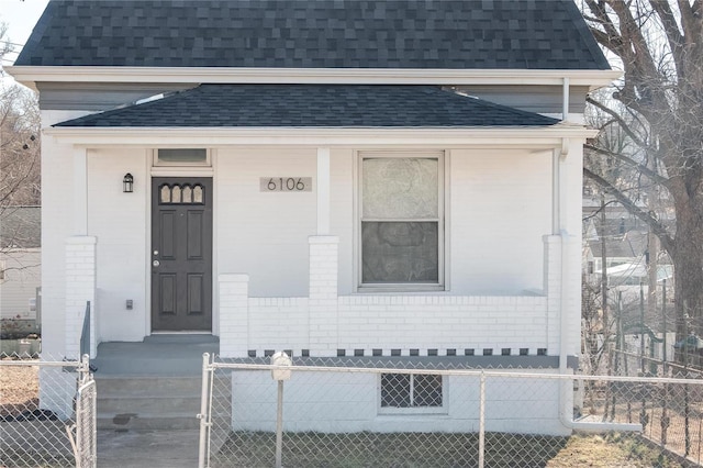 property entrance with roof with shingles, brick siding, and fence