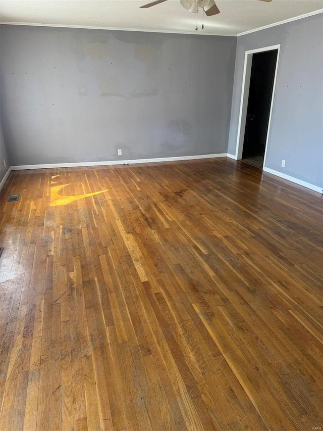 unfurnished room featuring dark wood-type flooring, visible vents, a ceiling fan, baseboards, and ornamental molding