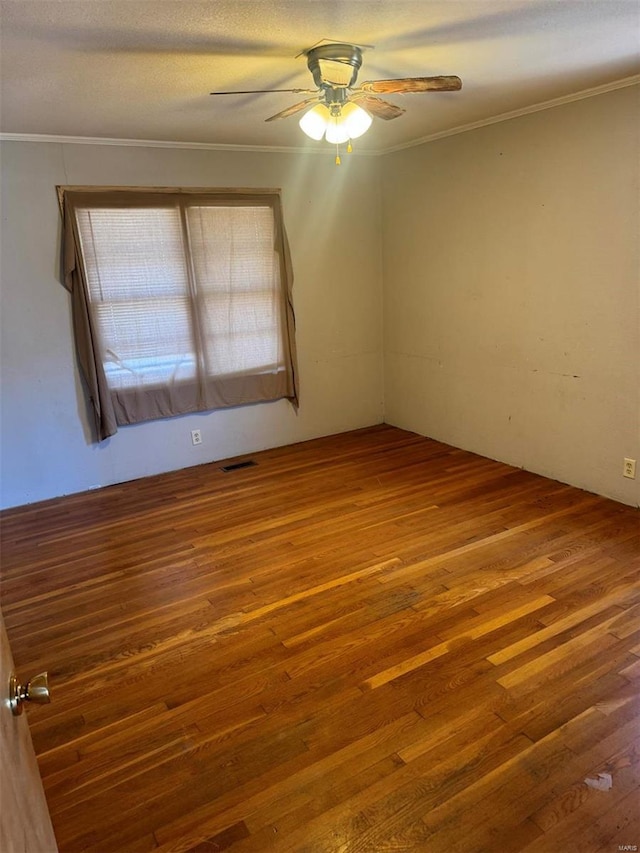 unfurnished room featuring crown molding, visible vents, ceiling fan, and wood finished floors