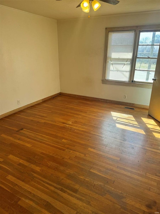 unfurnished room featuring visible vents, baseboards, and wood finished floors