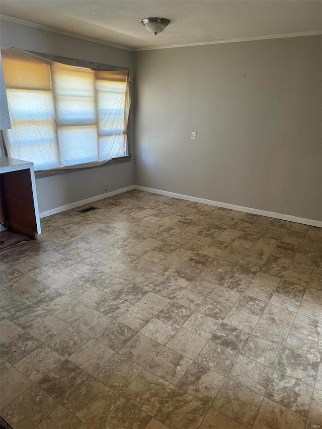 spare room with ornamental molding, visible vents, and baseboards