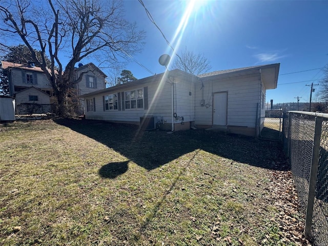 back of house with central air condition unit, fence, and a lawn