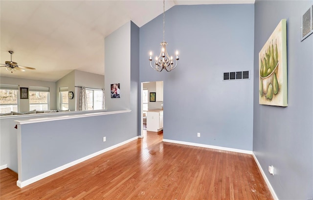 interior space featuring baseboards, visible vents, wood finished floors, high vaulted ceiling, and ceiling fan with notable chandelier