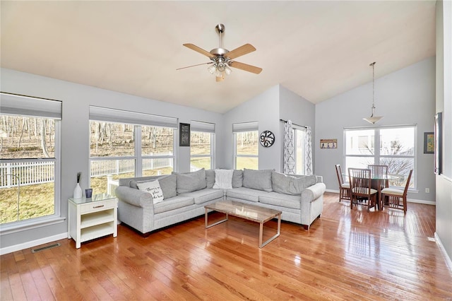 living area with visible vents, a ceiling fan, high vaulted ceiling, baseboards, and hardwood / wood-style flooring