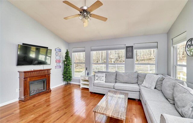 living area with vaulted ceiling, wood finished floors, and a healthy amount of sunlight