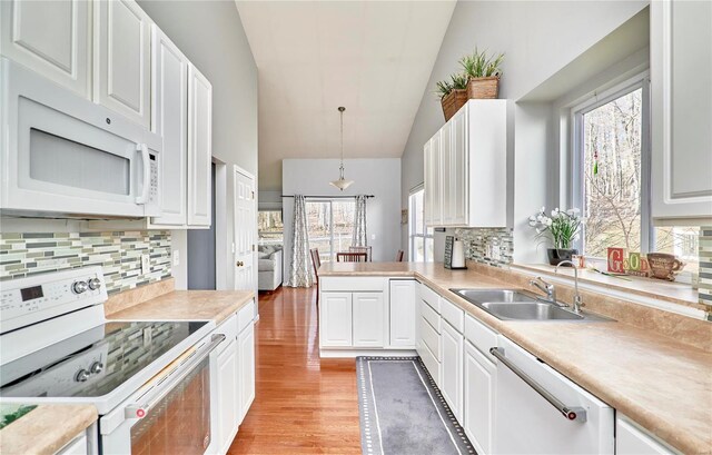 kitchen with hanging light fixtures, white appliances, a sink, and light countertops