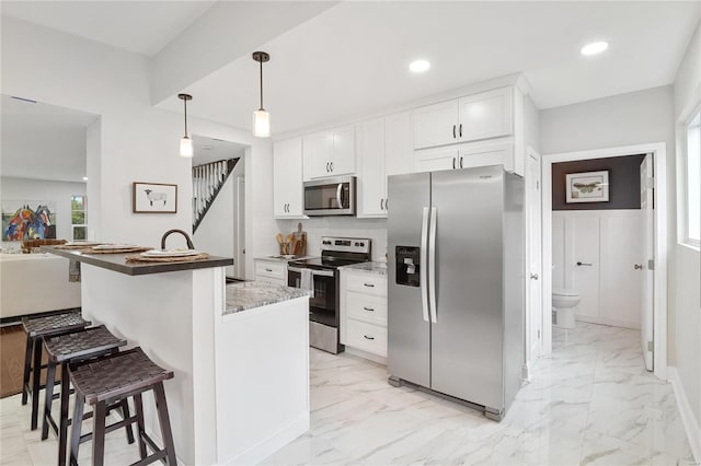 kitchen with marble finish floor, appliances with stainless steel finishes, white cabinetry, and a kitchen breakfast bar