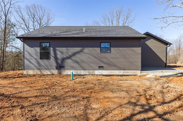 view of home's exterior with roof with shingles and crawl space