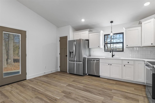 kitchen with light wood-style flooring, a sink, white cabinets, appliances with stainless steel finishes, and tasteful backsplash