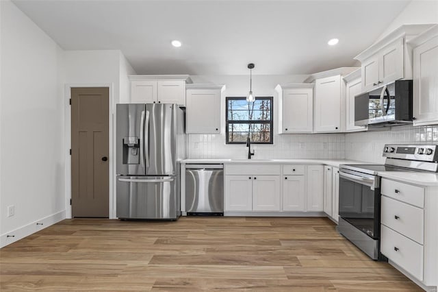 kitchen featuring decorative backsplash, white cabinetry, stainless steel appliances, and a sink