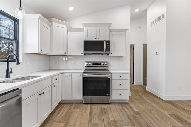 kitchen featuring light wood-style flooring, stainless steel appliances, a sink, visible vents, and light countertops