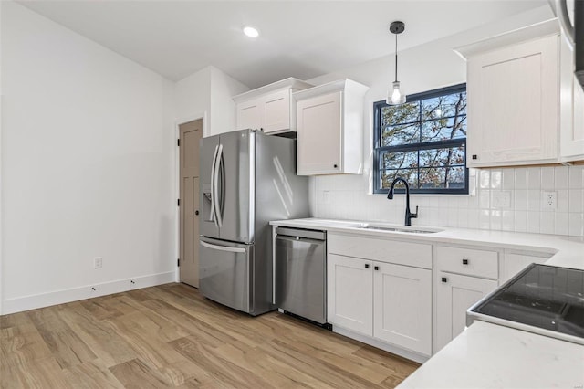 kitchen featuring stainless steel appliances, tasteful backsplash, a sink, and light wood-style flooring